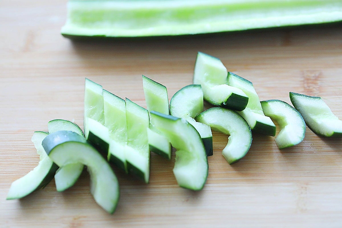 Diagonal slices of Japanese cucumber on a chopping board.