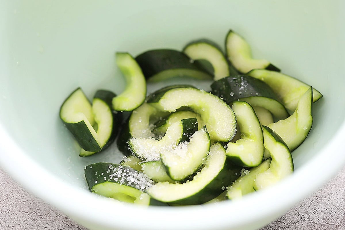 Cucumber slices, Chinese rice vinegar and sugar in a bowl.