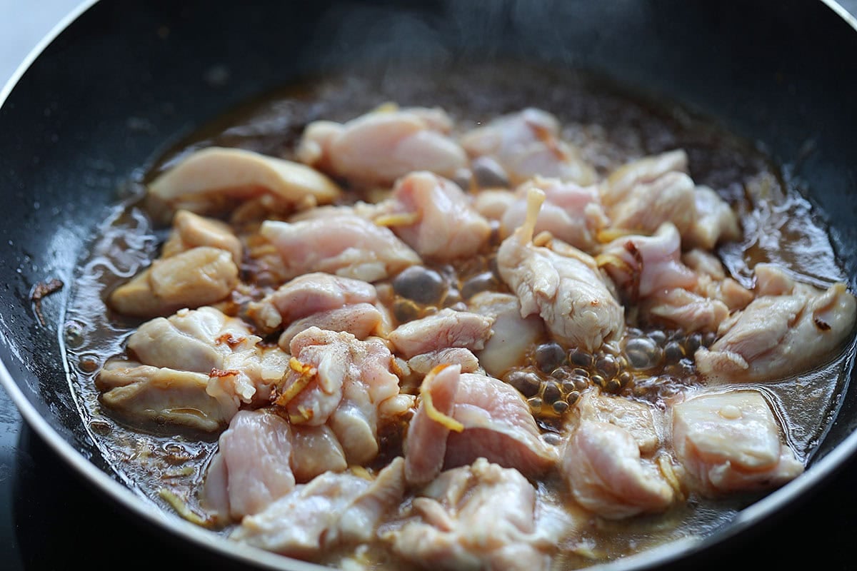 Chicken, ginger strips and seasoning in a pan.