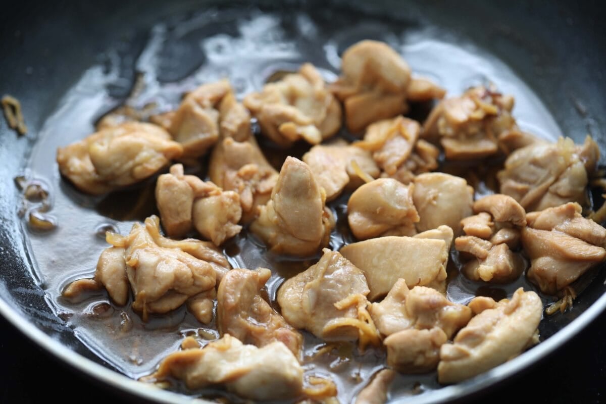 Tender sesame oil chicken with golden brown ginger strips in a pan.