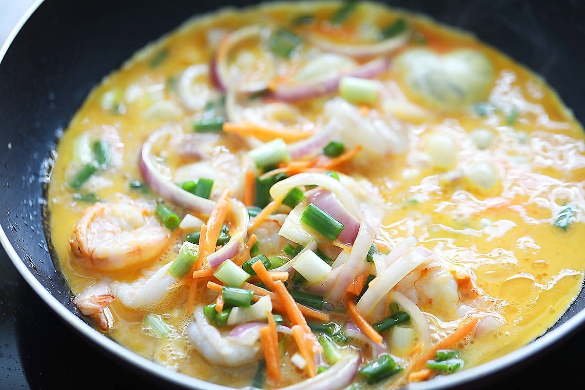 Egg mixture and shrimp in a skillet.