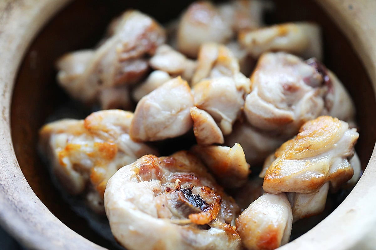 Crispy, golden brown chicken in a clay pot.