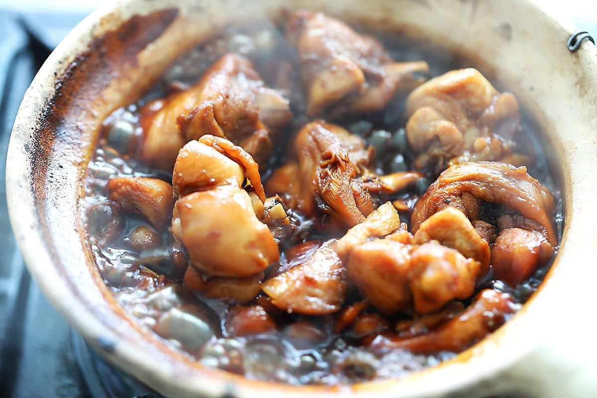 Chicken simmering in a clay pot with soy sauce, Shaoxing wine, and sesame oil.