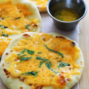 Cheese naan served alongside garlic butter.