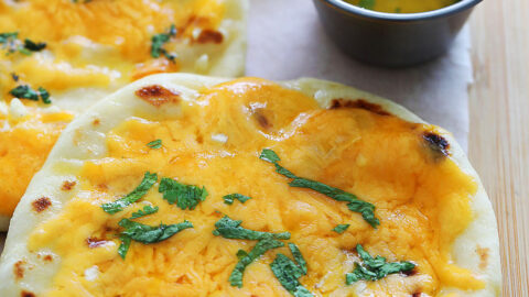 Cheese naan served alongside garlic butter.