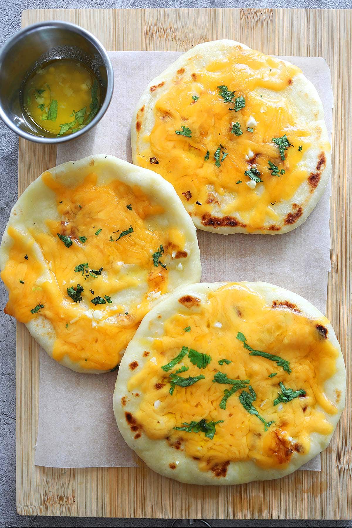 Homemade cheesy garlic naan served on a board.