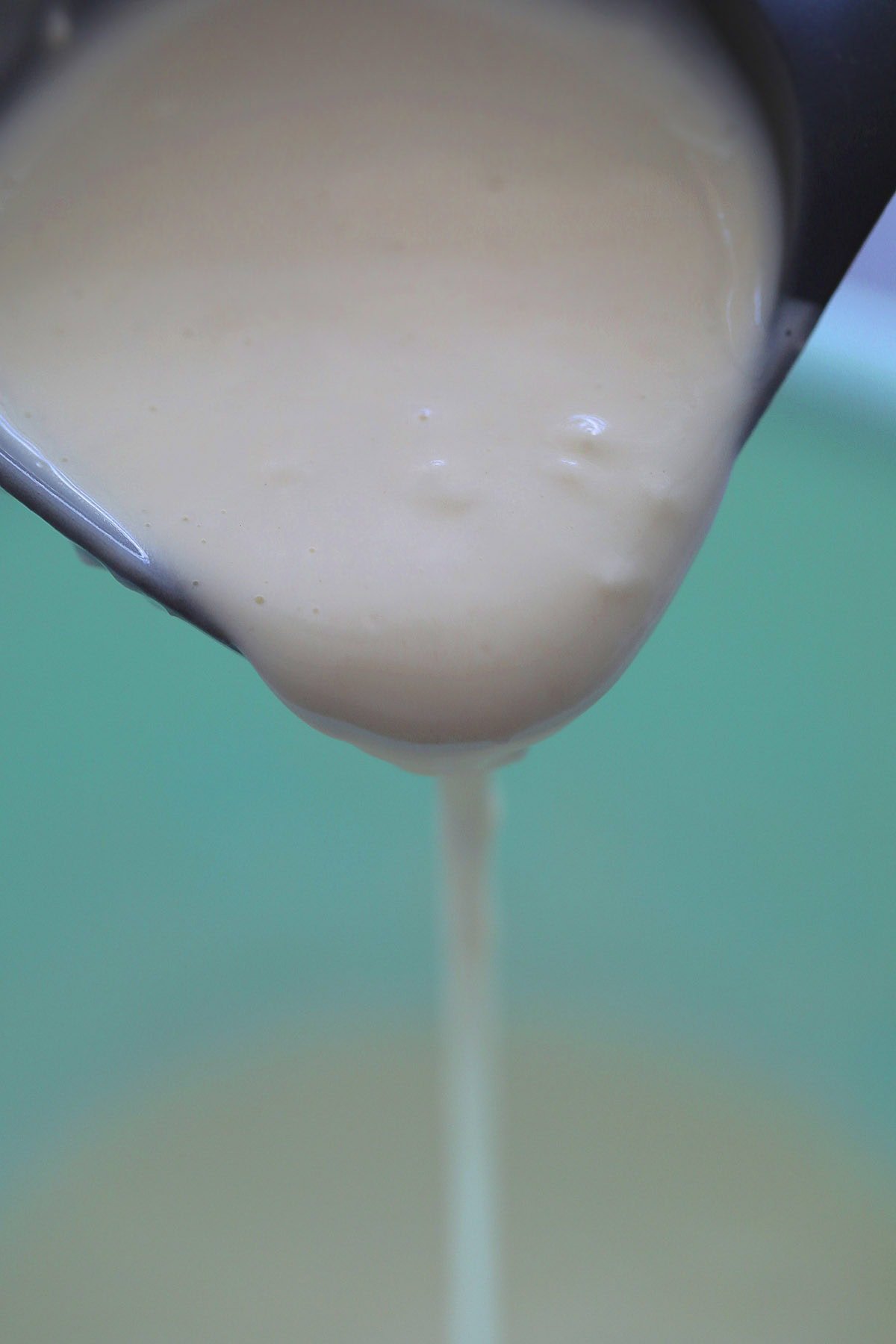 Crispy frying batter poured from ladle.