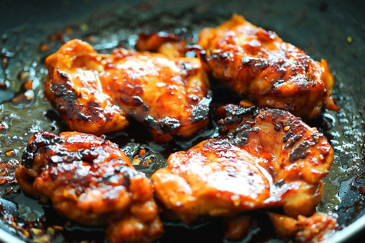 Juicy spicy Korean chicken thighs in a skillet.