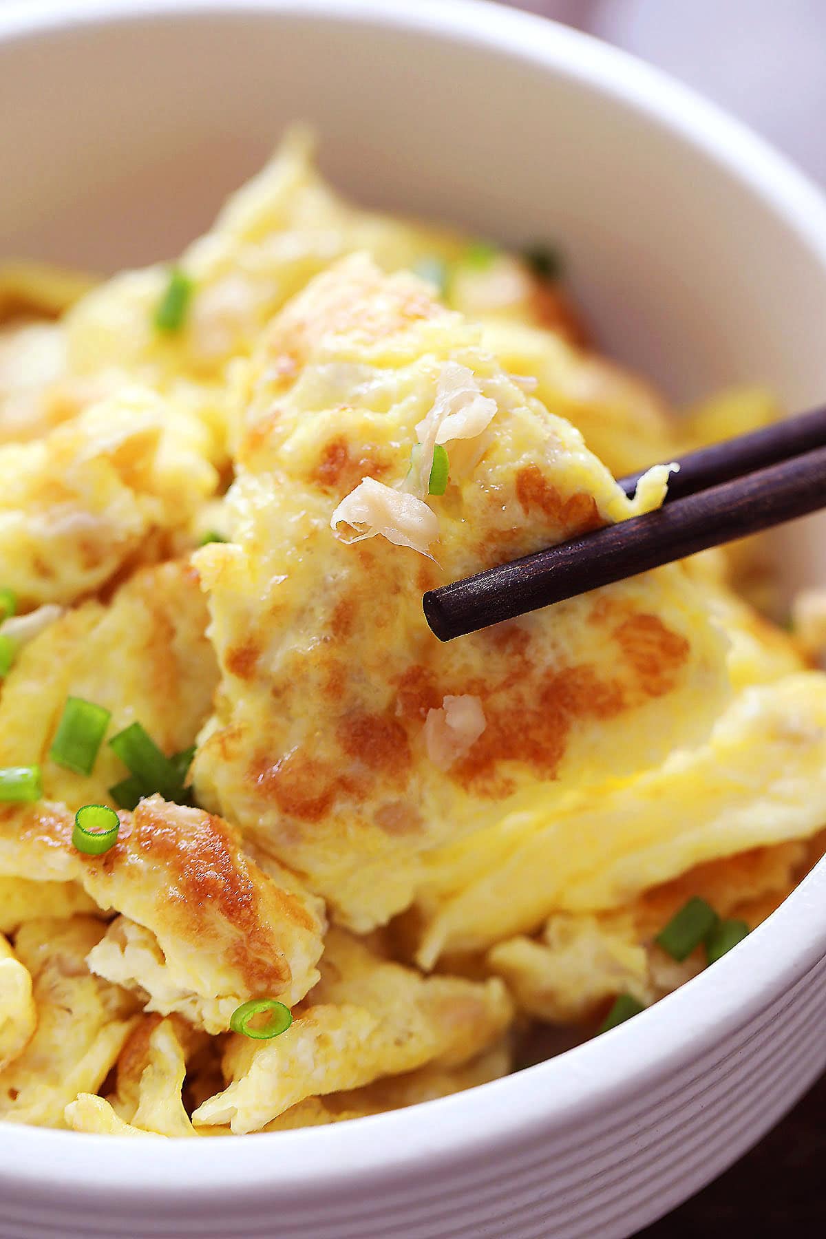 Scrambled eggs with preserved radish (chai poh) picked with a pair of chopsticks.