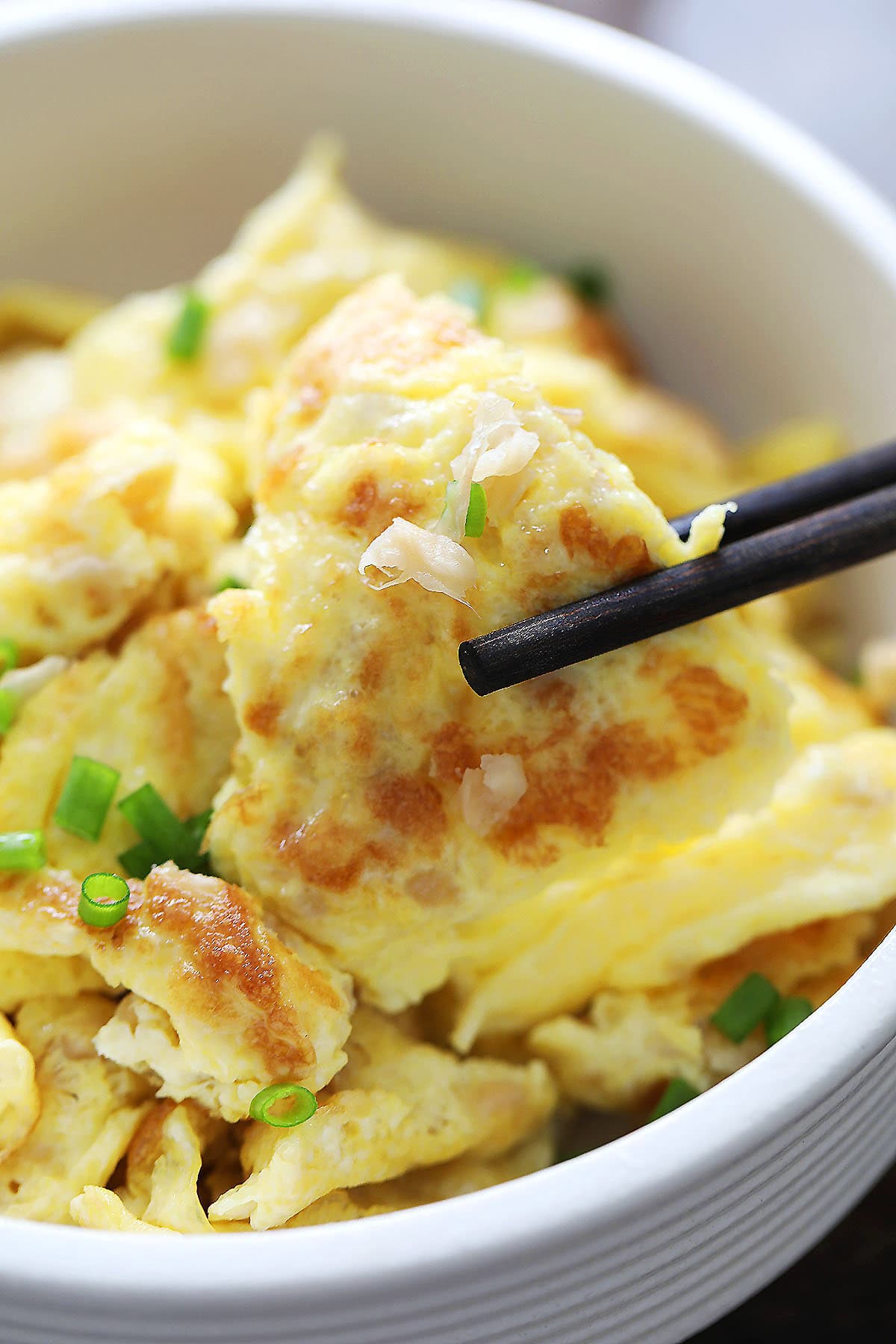 Scrambled eggs with preserved turnip (chai poh) picked with a pair of chopsticks.