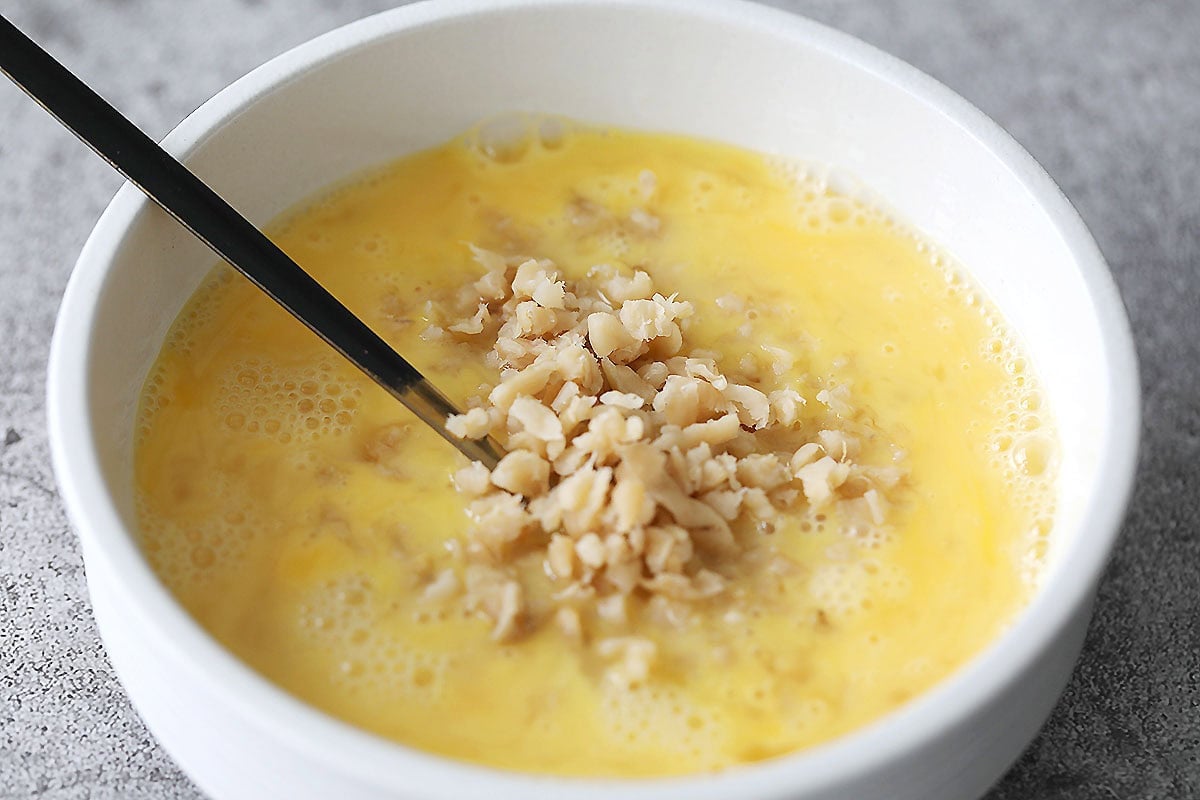Beaten eggs and preserved turnip in a bowl.