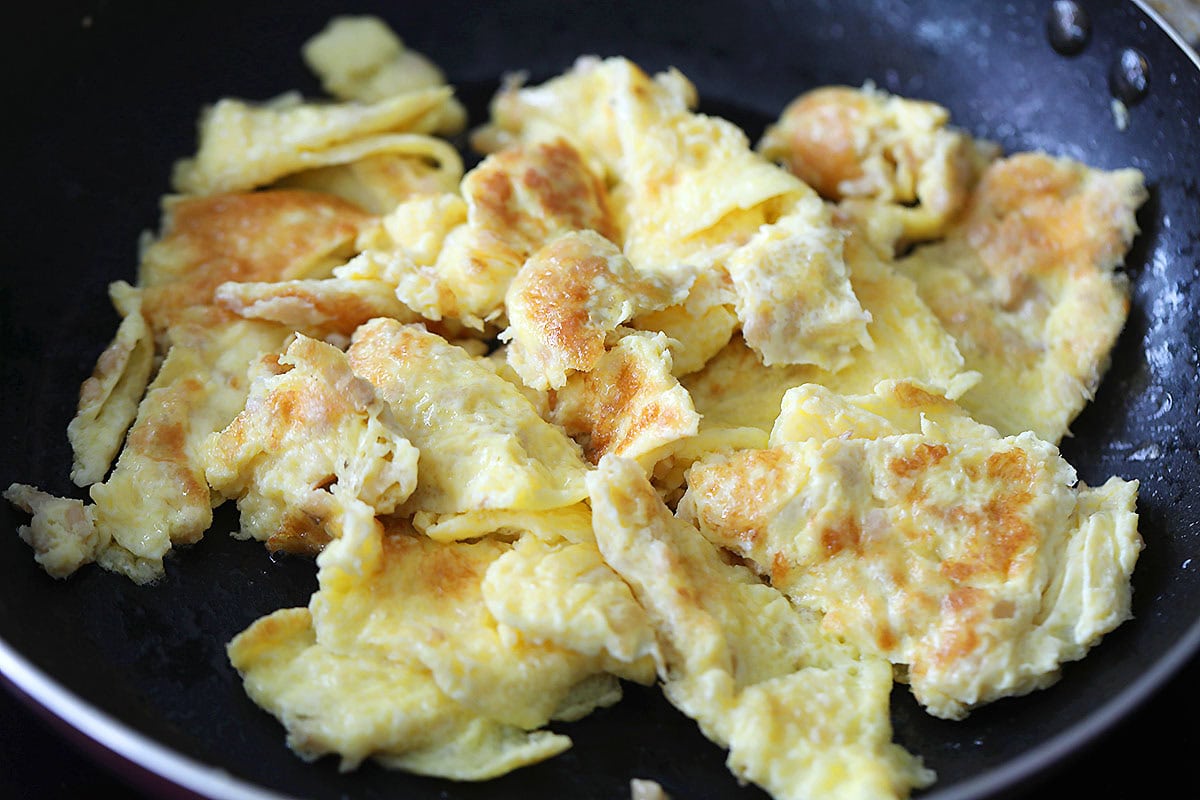 Stir fried eggs with preserved radish in a skillet.