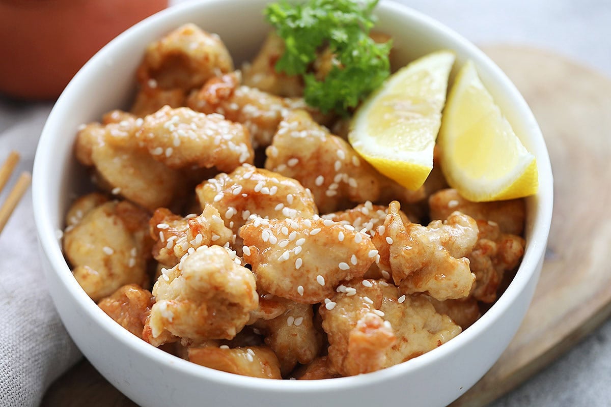 Crispy Chinese lemon chicken topped with white sesame seeds.