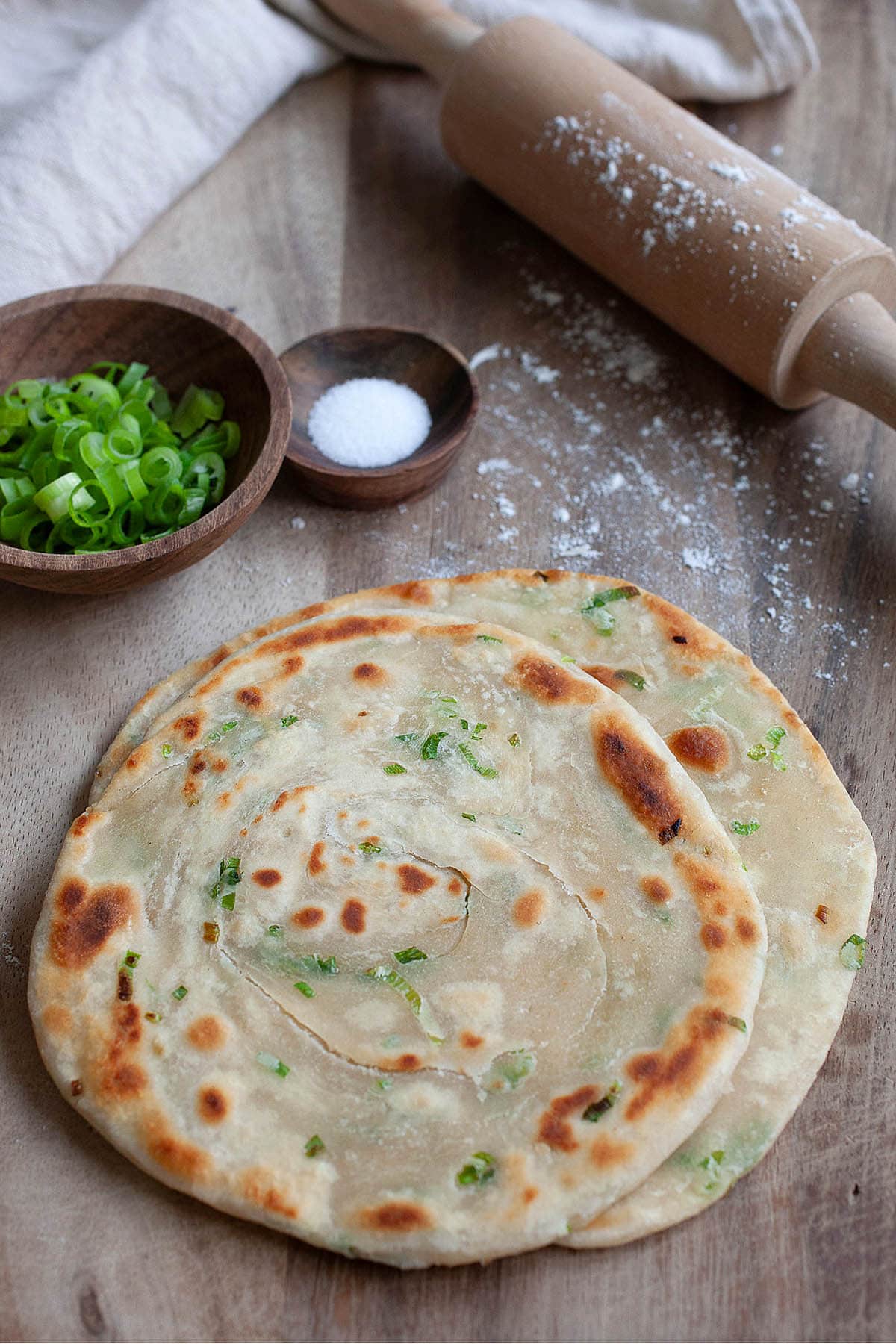 Crispy scallion pancakes on a wooden board.