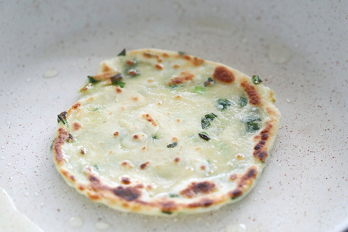 Crispy scallion pancake in a pan.