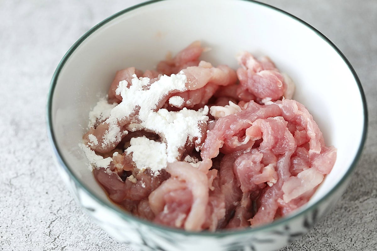 Pork and cornstarch in a bowl.