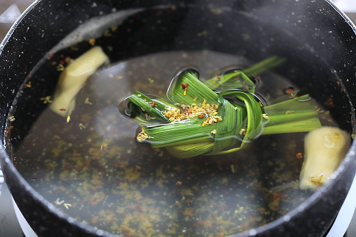 Sweet ginger soup in a pot with pandan leaves and osmanthus.