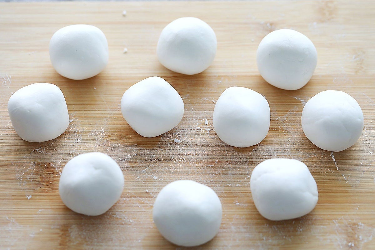 Portioned raw dough balls on a chopping board.