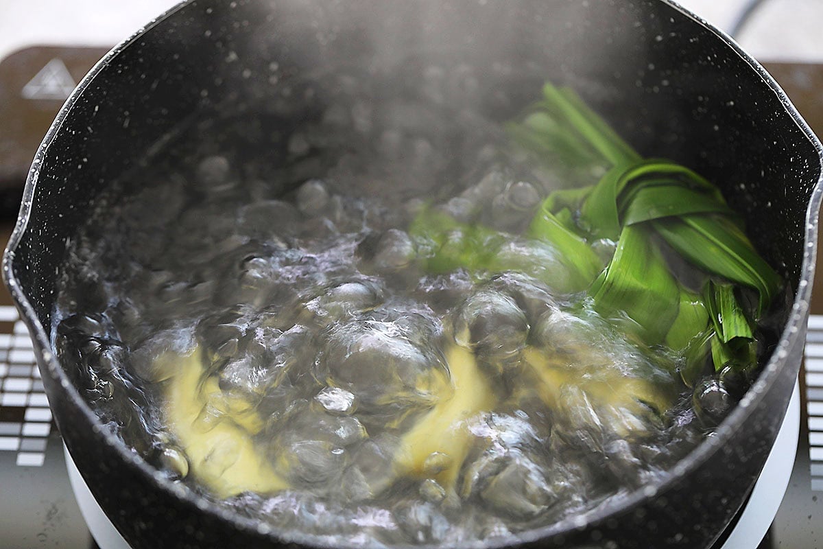 Pandan leaves and ginger in a pot of boiling water.