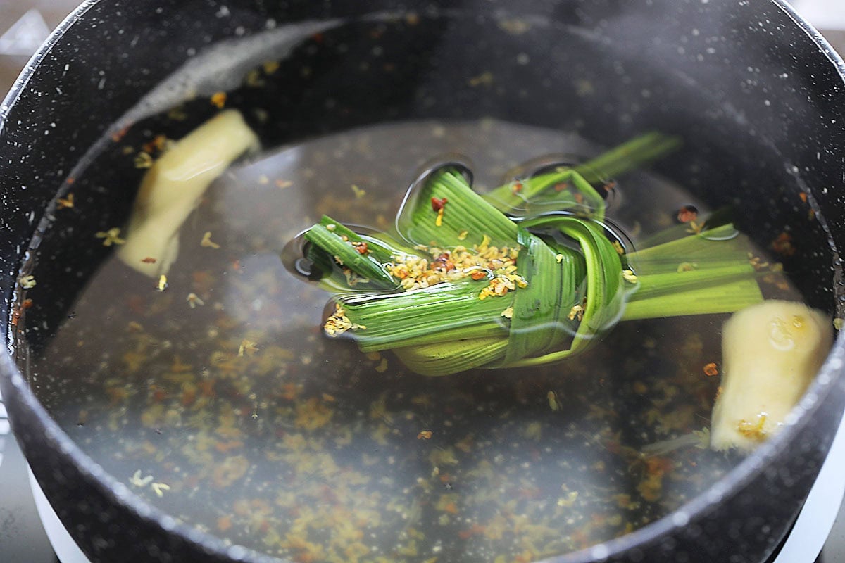 Ginger, pandan leaves, and sweet osmanthus in a pot of water.