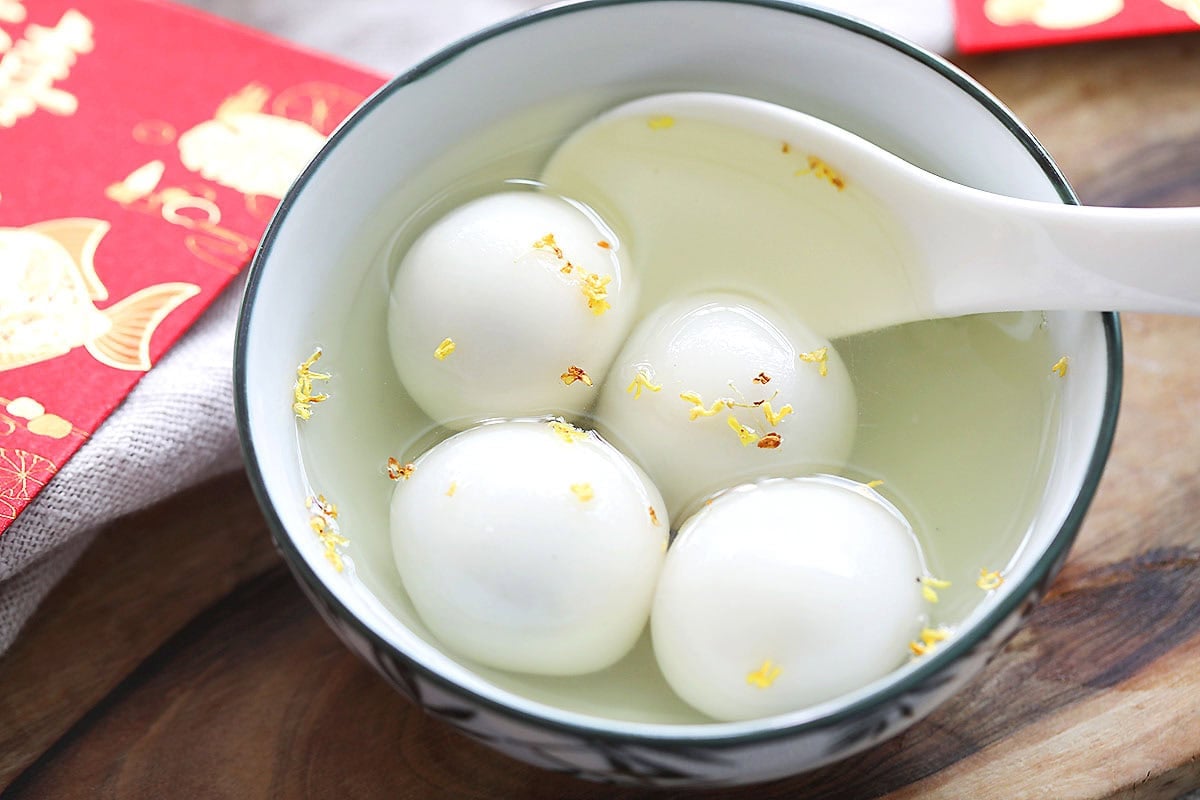 Black sesame tang yuan in a bowl of warm ginger syrup.