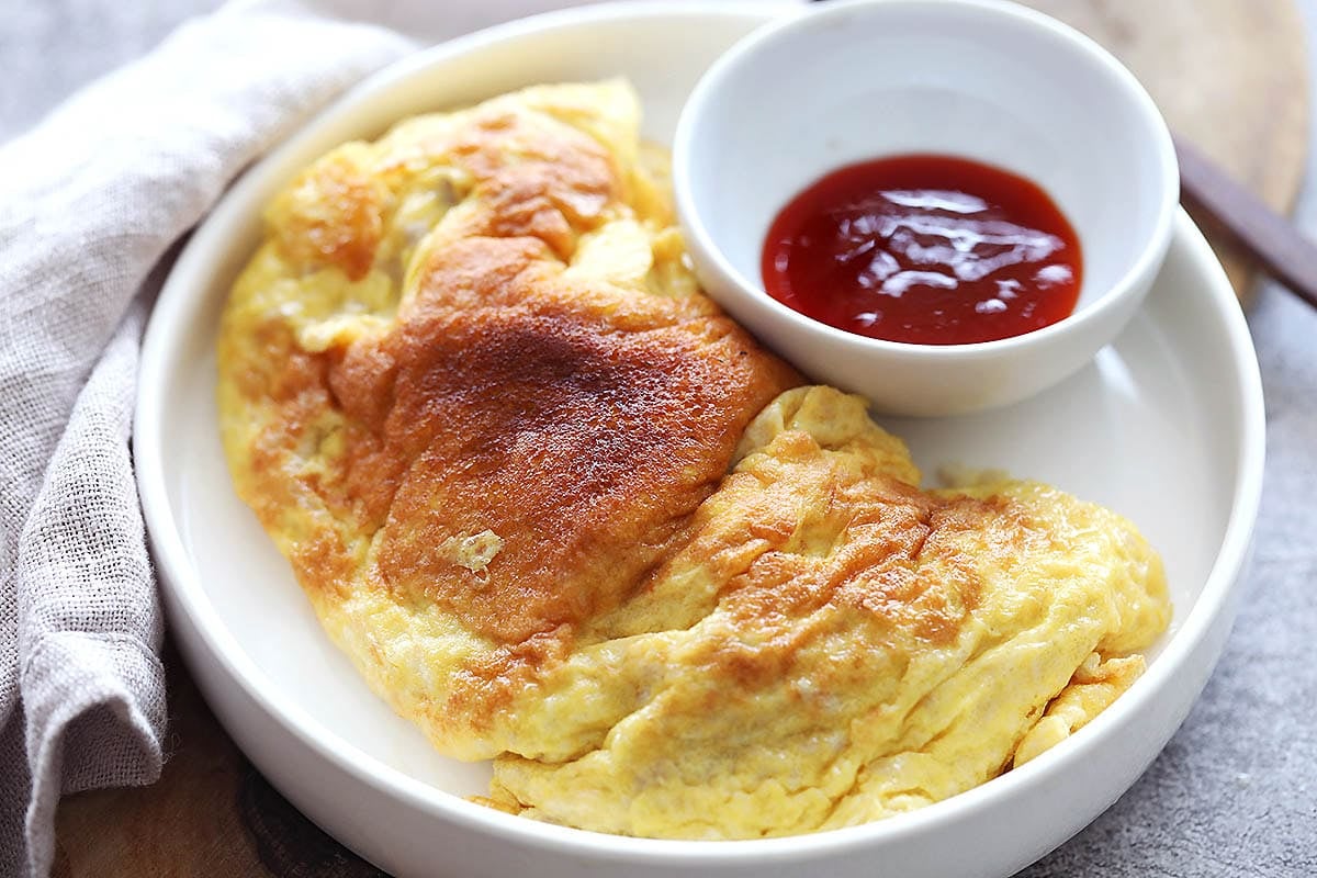 Fluffy, golden brown Thai pork omelette served with chili sauce.