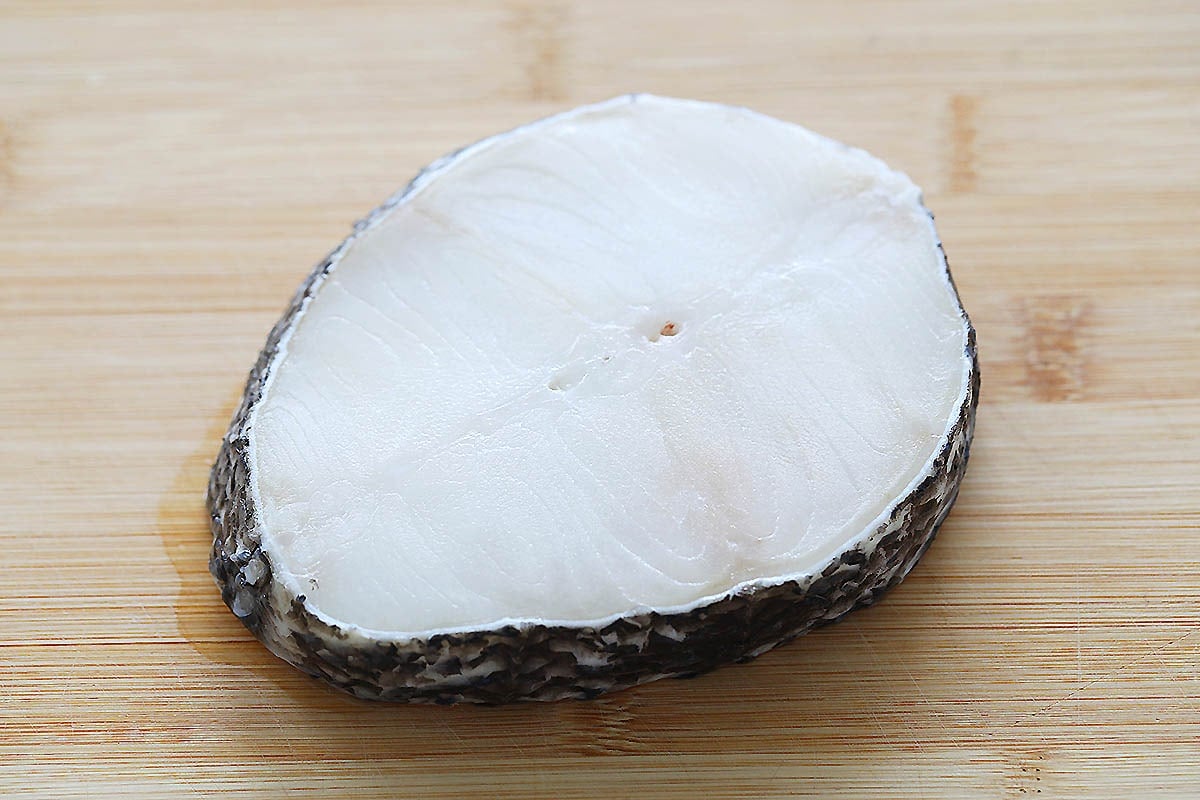 Black cod fillet on a chopping board.
