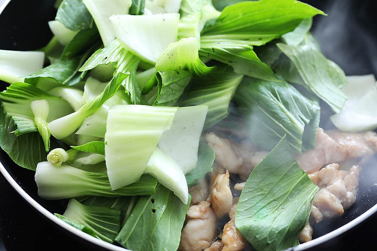 Chicken and bok choy in a pan.