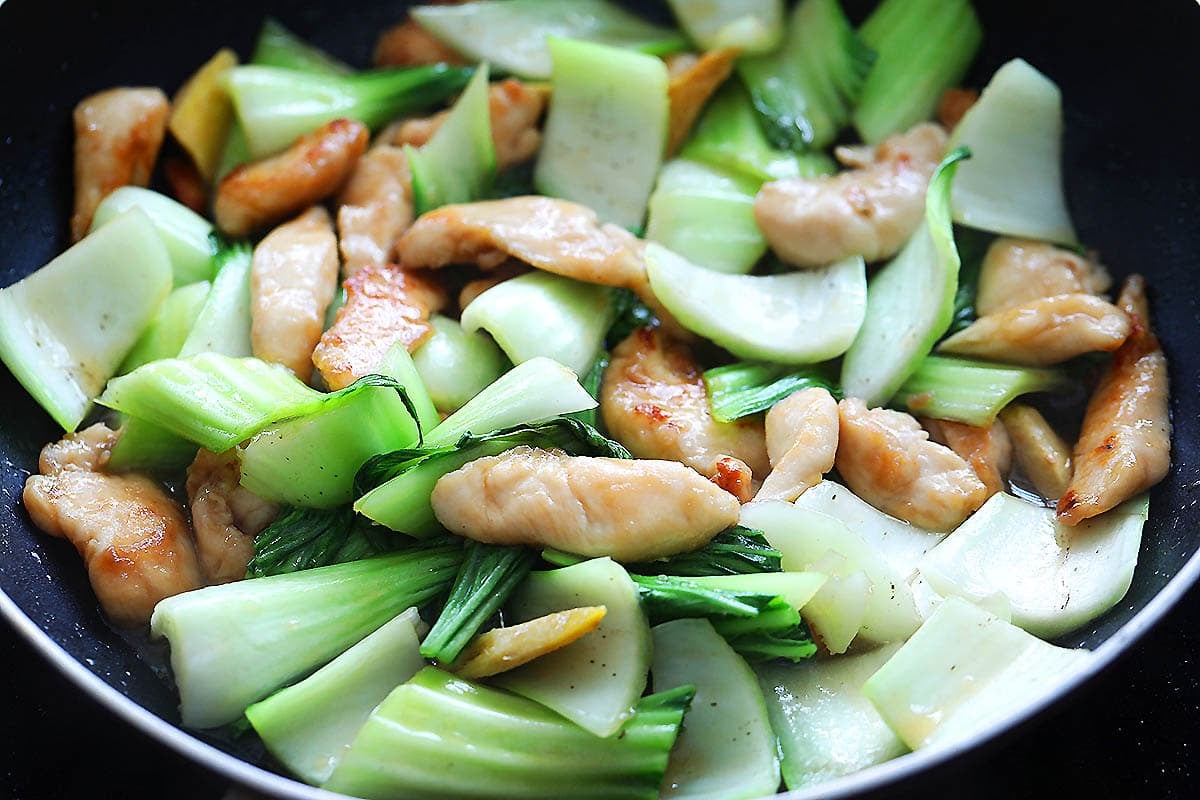 Bok choy and chicken in a pan.