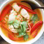 Easy Thai chicken noodle soup recipe garnished with Thai chilies and cilantro.
