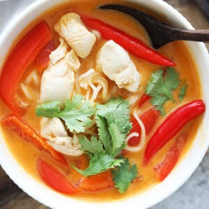 Easy Thai chicken noodle soup recipe garnished with Thai chilies and cilantro.