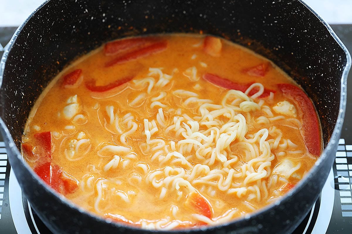 Thai coconut chicken soup with ramen noodles in a pot.