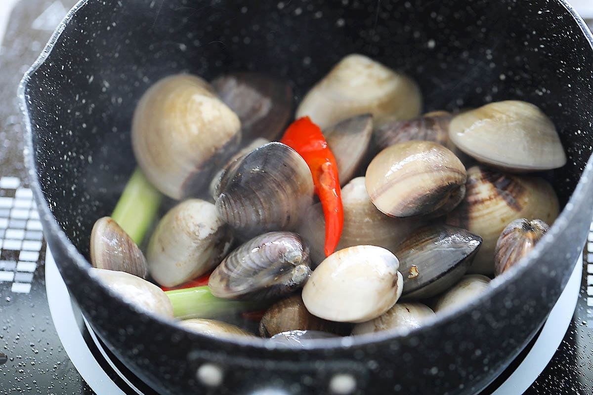 Manila clams, bird's eyes chilies and lemongrass in a pot.