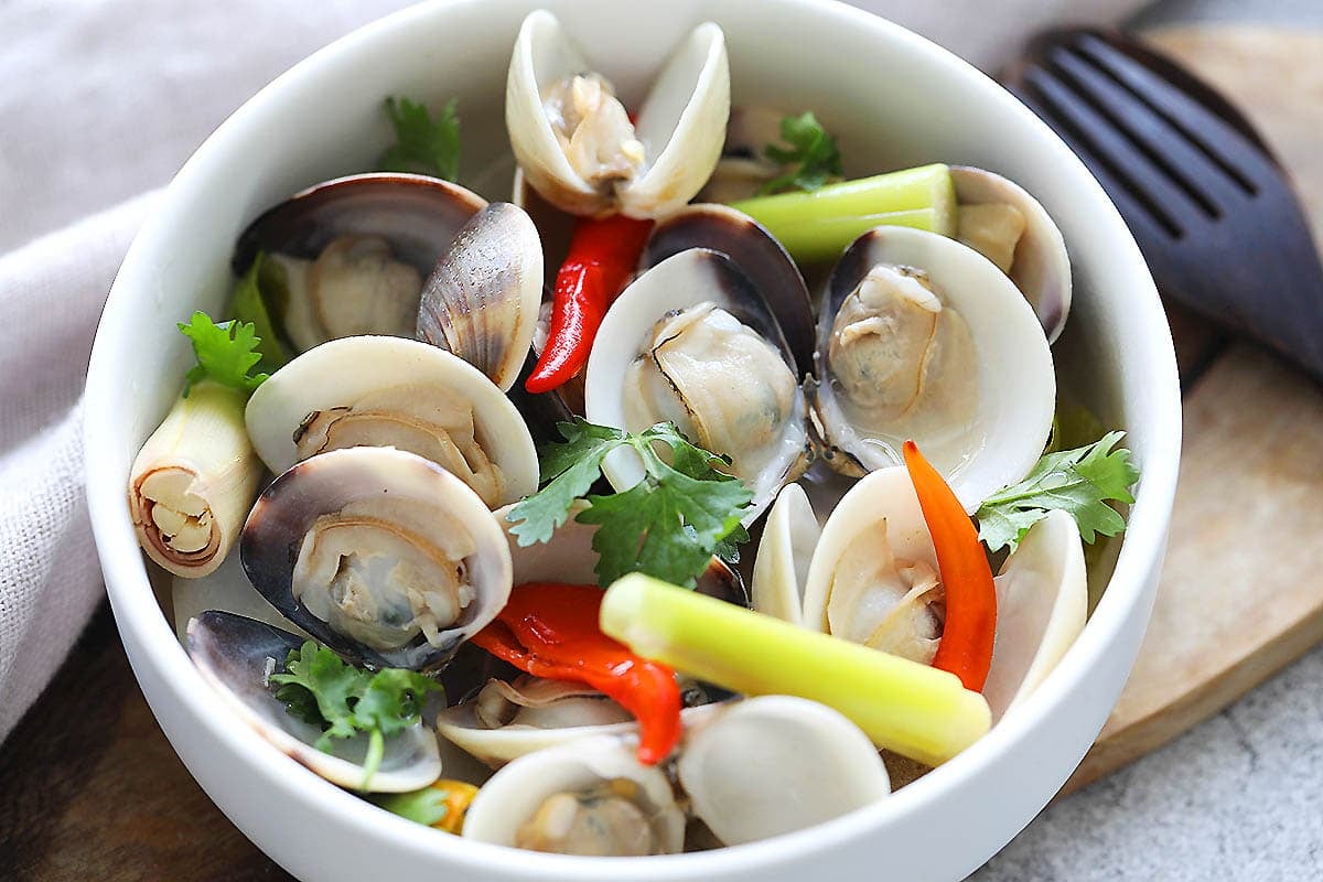 Thai style steamed clams with coconut water, lemongrass, and chilies, served in a bowl.