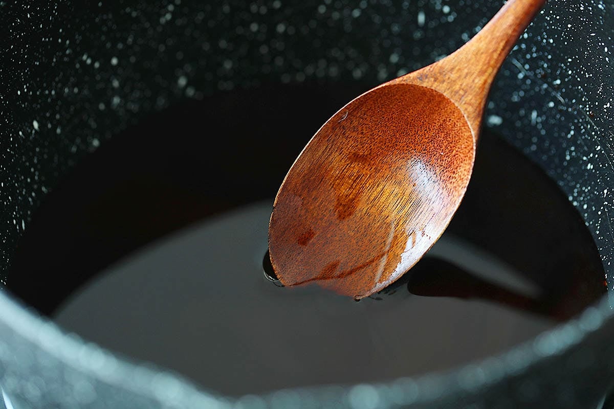 Wooden spoon in a sauce pan with kung pao sauce.