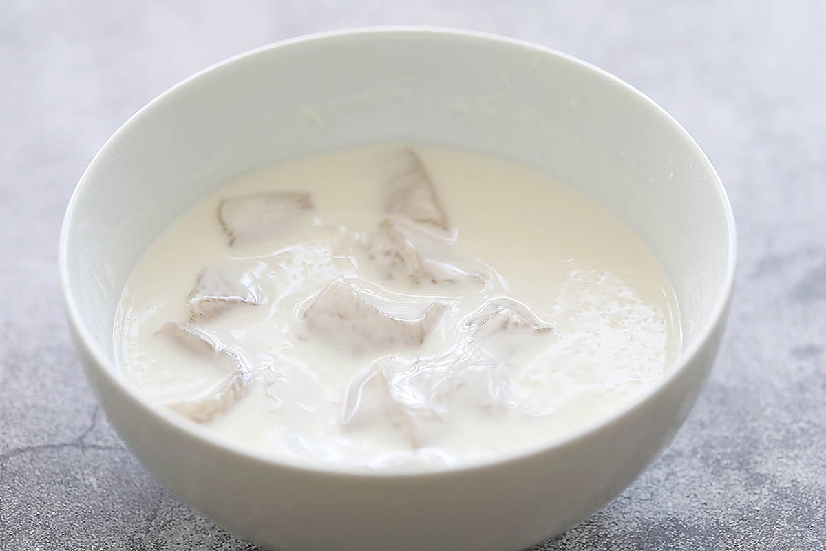 Chicken cubes in a bowl of frying batter.