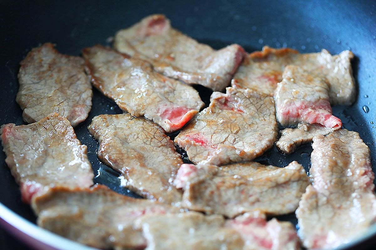 Stir-fried beef in pan.