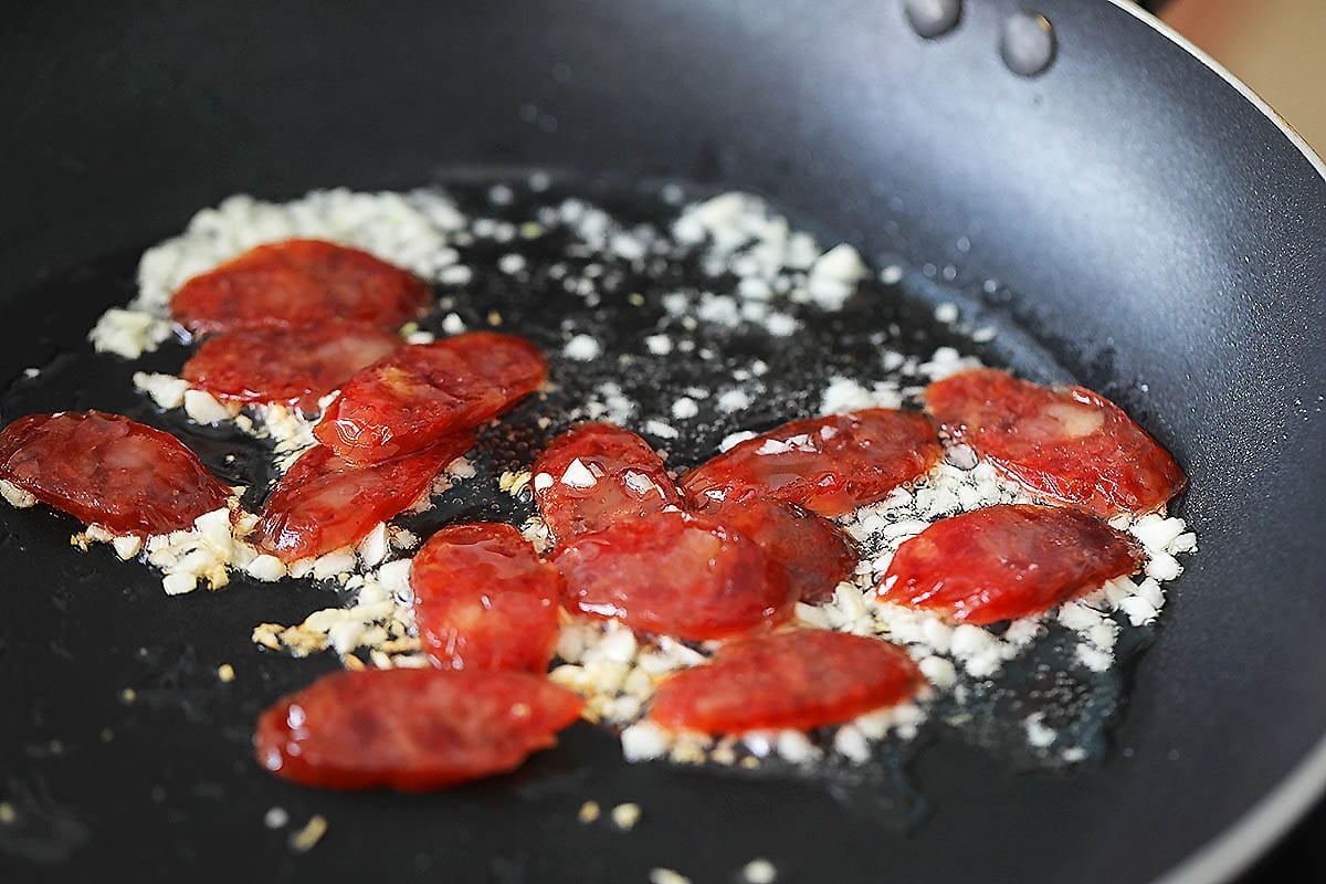 Chinese sausage and minced garlic in a pan.