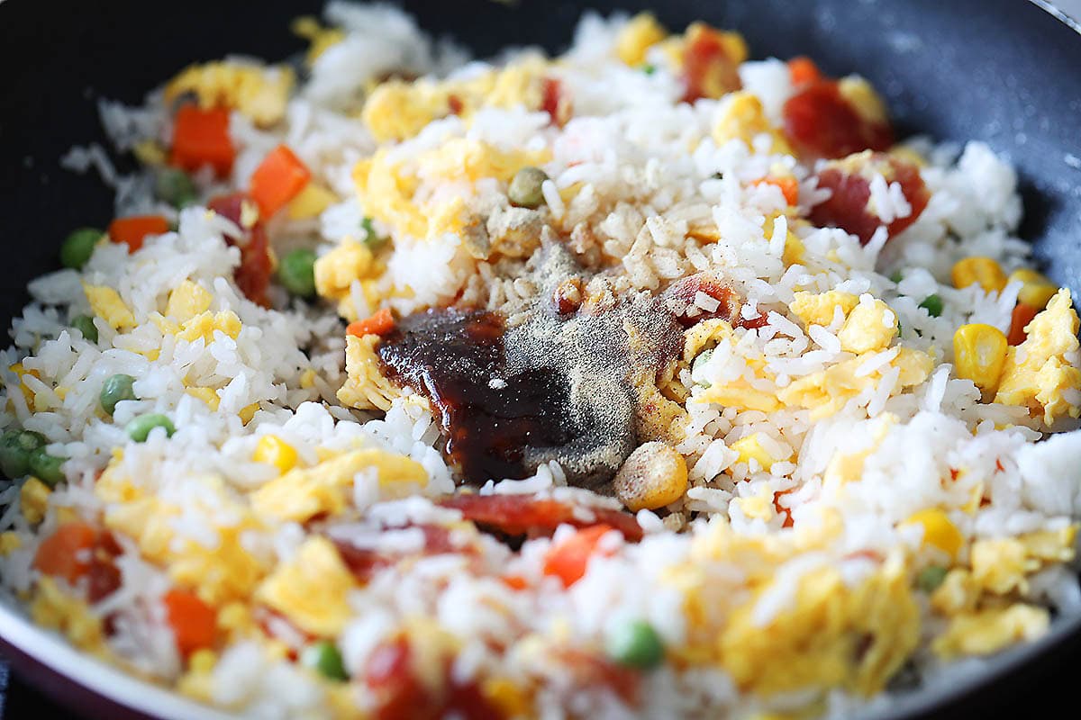 Eggs, mixed vegetables, rice, and seasonings in a pan.