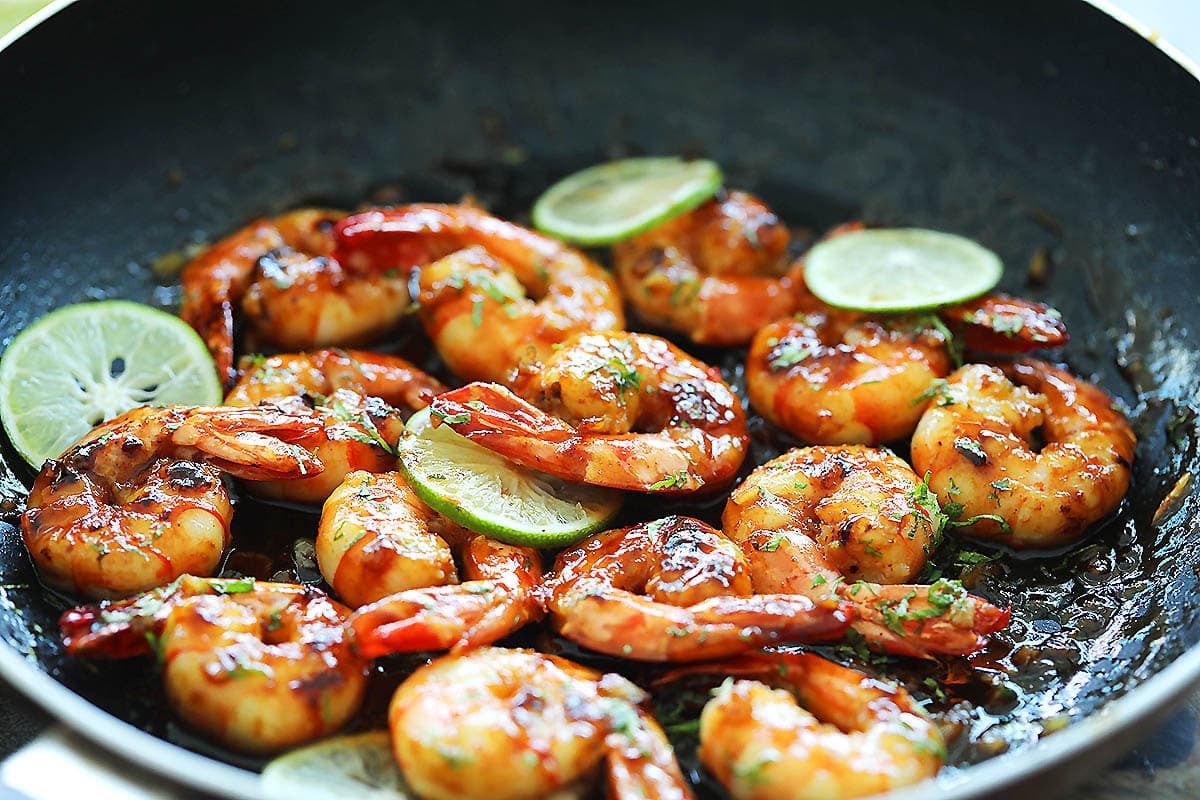 Honey lime shrimp garnished with lime slices and parsley in a skillet.