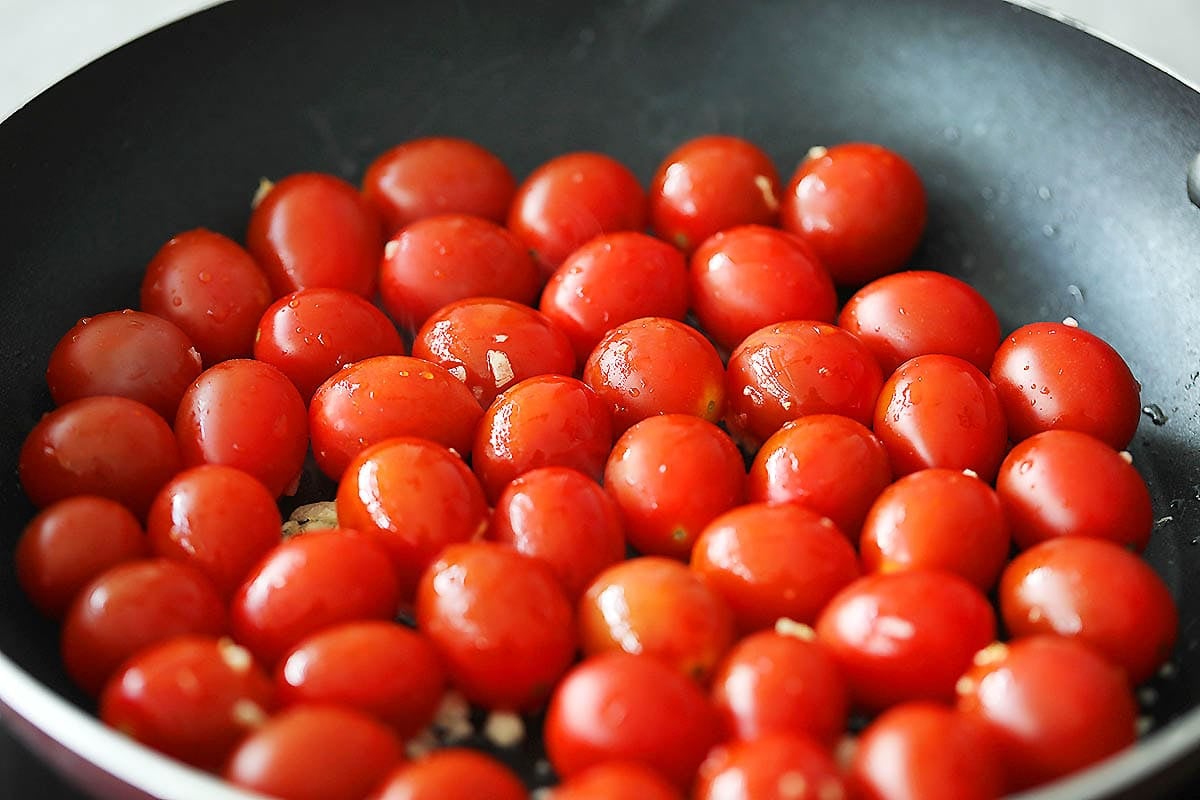 Cherry tomatoes in a pan with minced garlic.