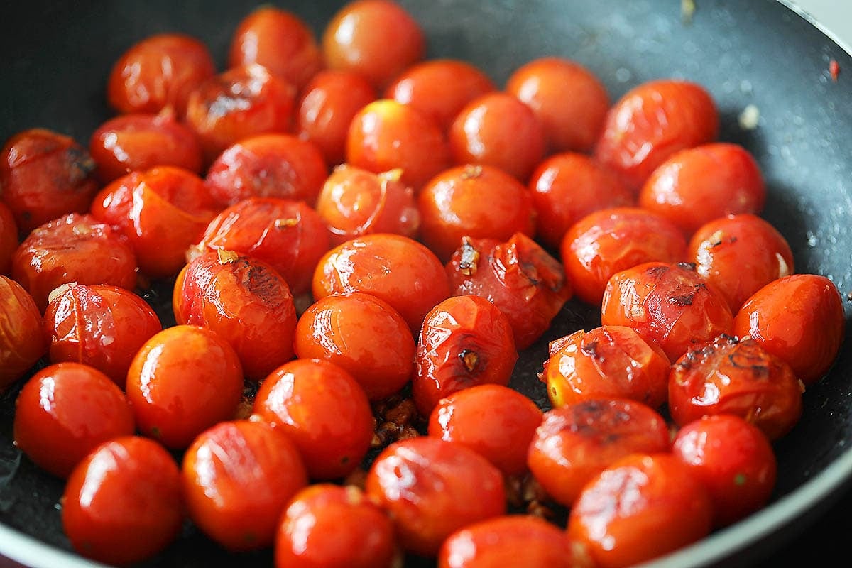 Charred cherry tomatoes in a pan.