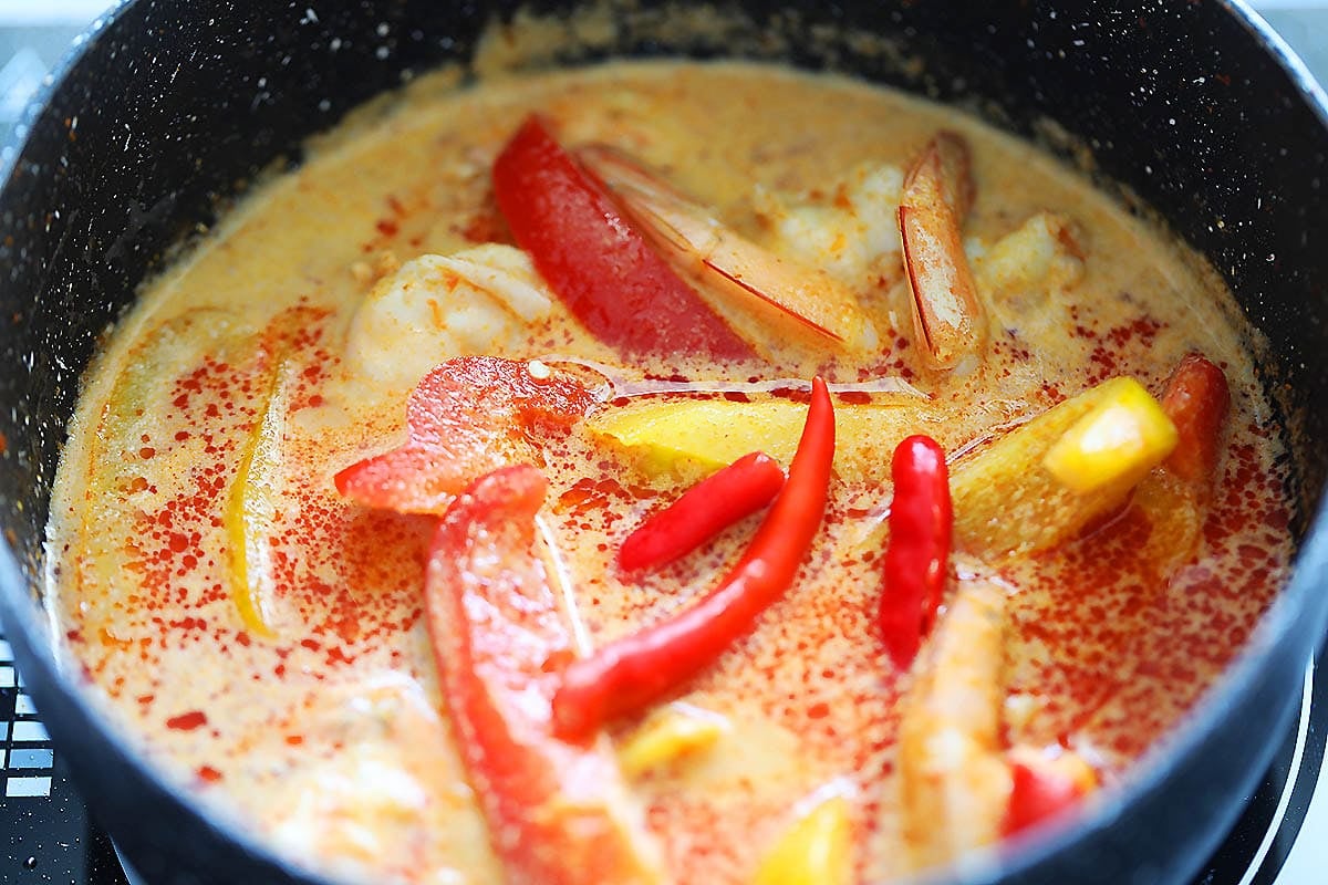 Thai red coconut curry with shrimp and bell peppers in a saucepan.