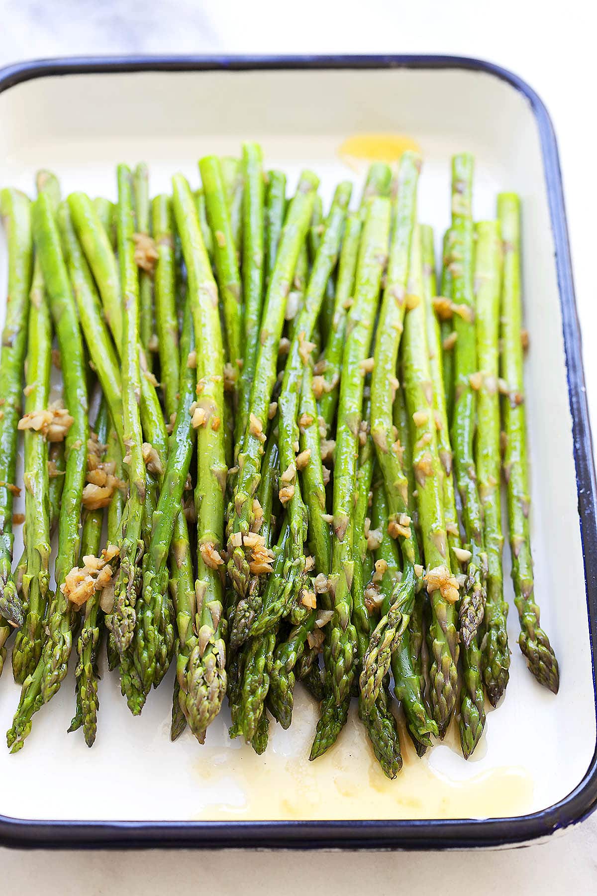 Garlic butter sauteed asparagus with lemon juice served on a tray.