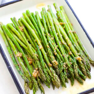 Sauteed asparagus with garlic butter served on a tray.