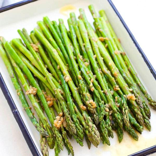 Sauteed asparagus with garlic butter served on a tray.