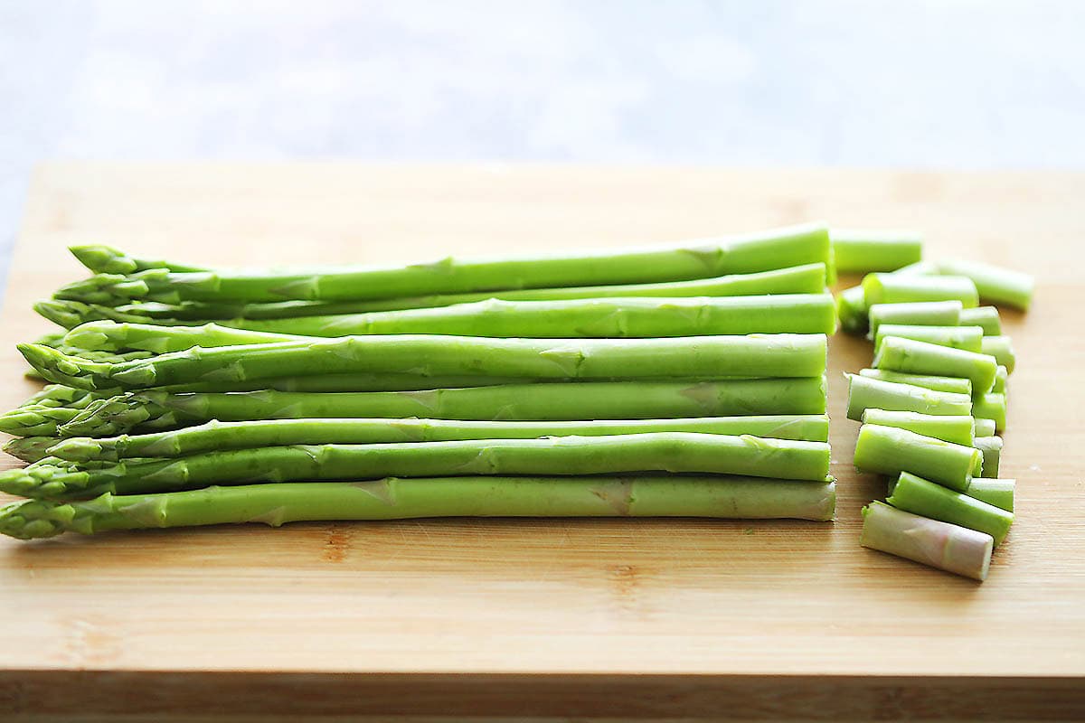 Bottom part of the asparagus trimmed on a chopping board.