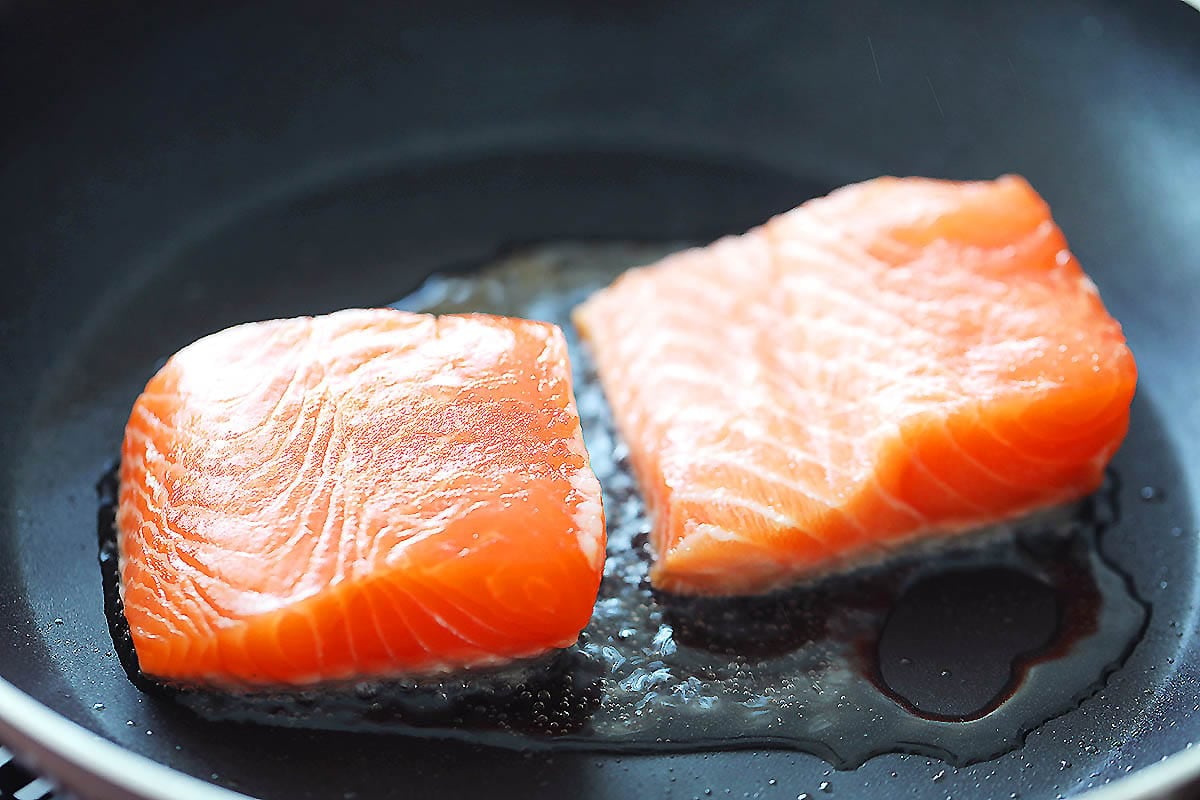 Pan-fried salmon fillets in a skillet.