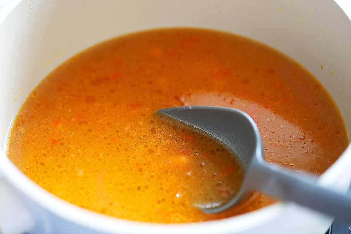 Seafood stock and tomato base in a pot.