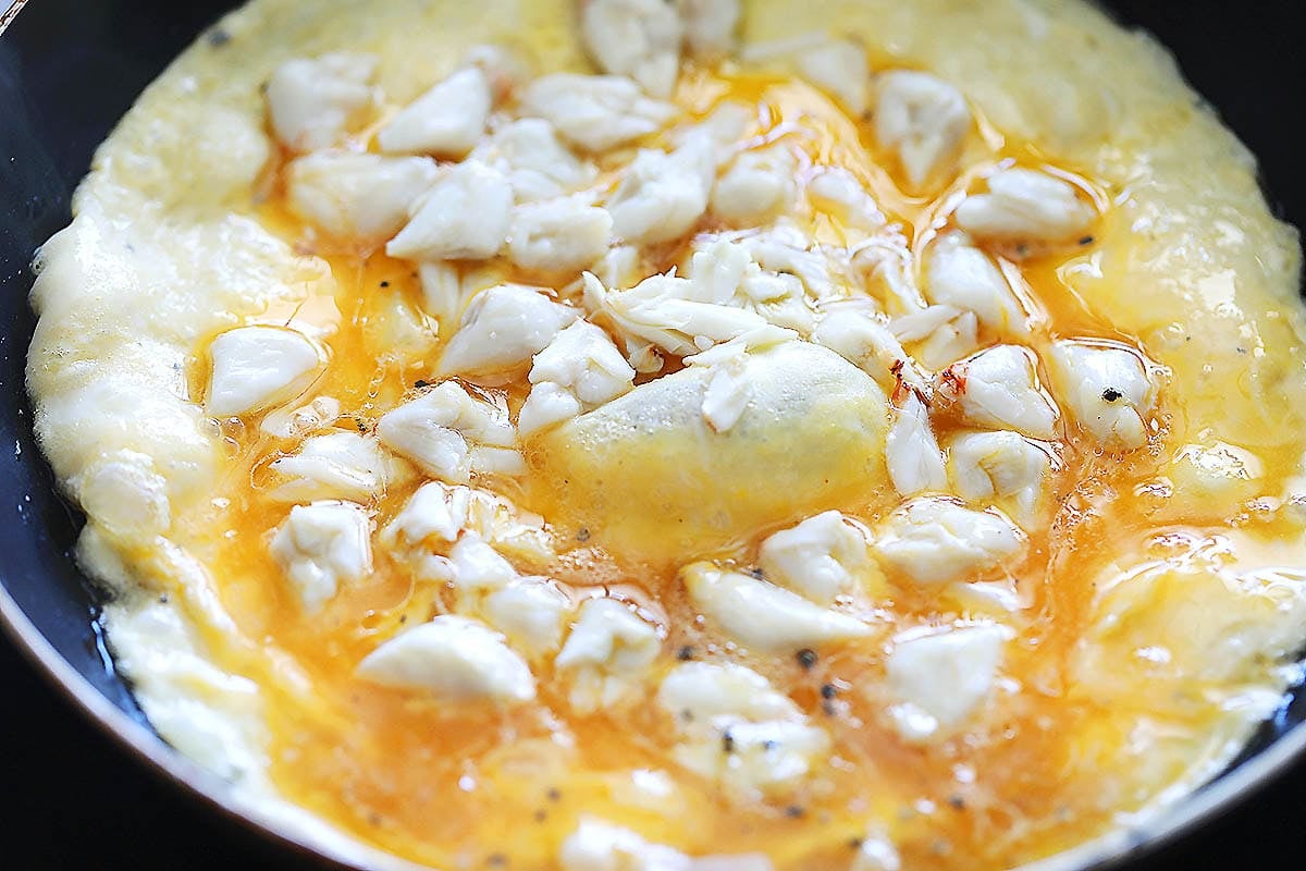 Egg mixture topped with lump crab meat in a skillet.
